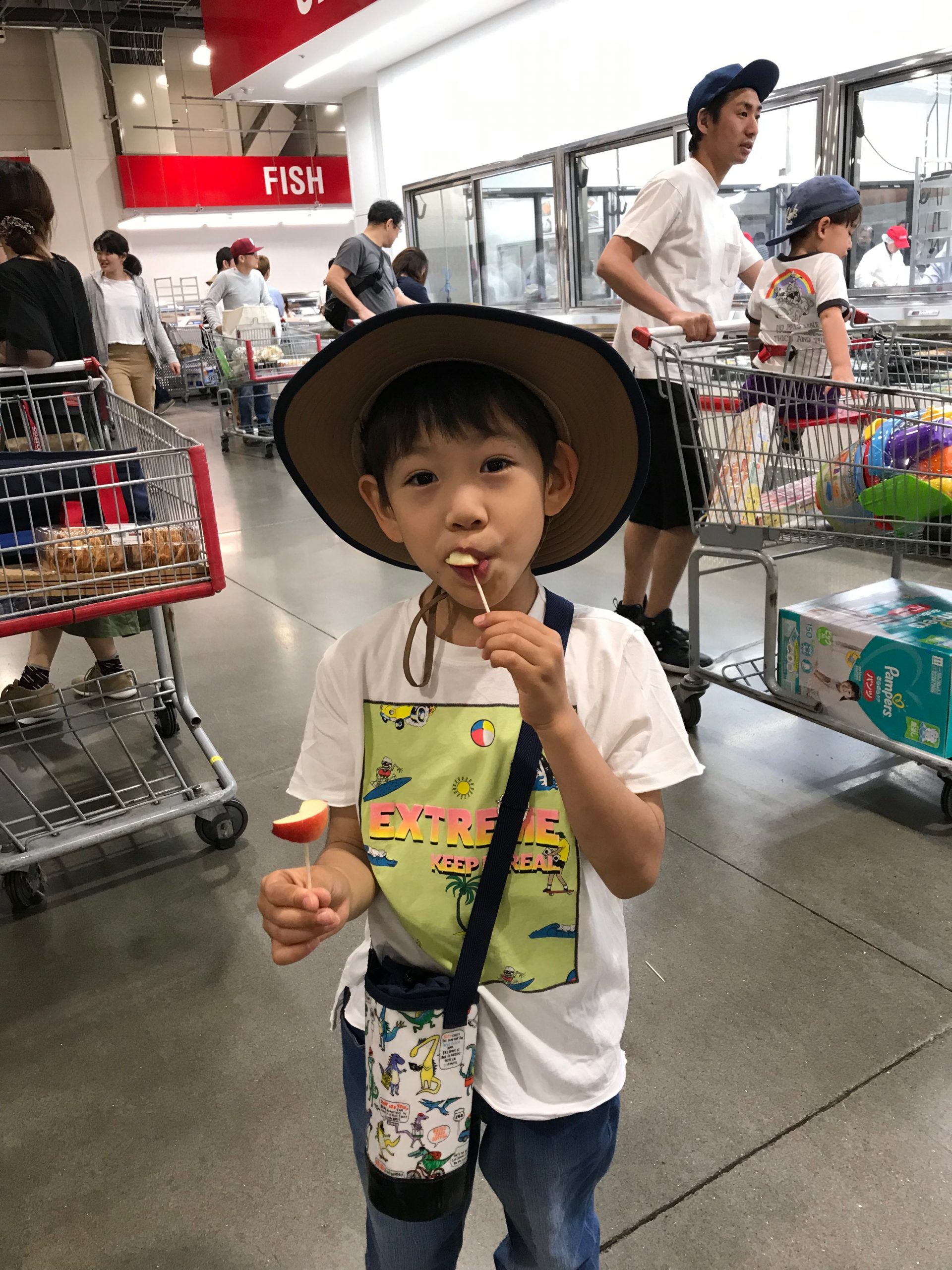 Young asian boy sampling Rockit apple in supermarket