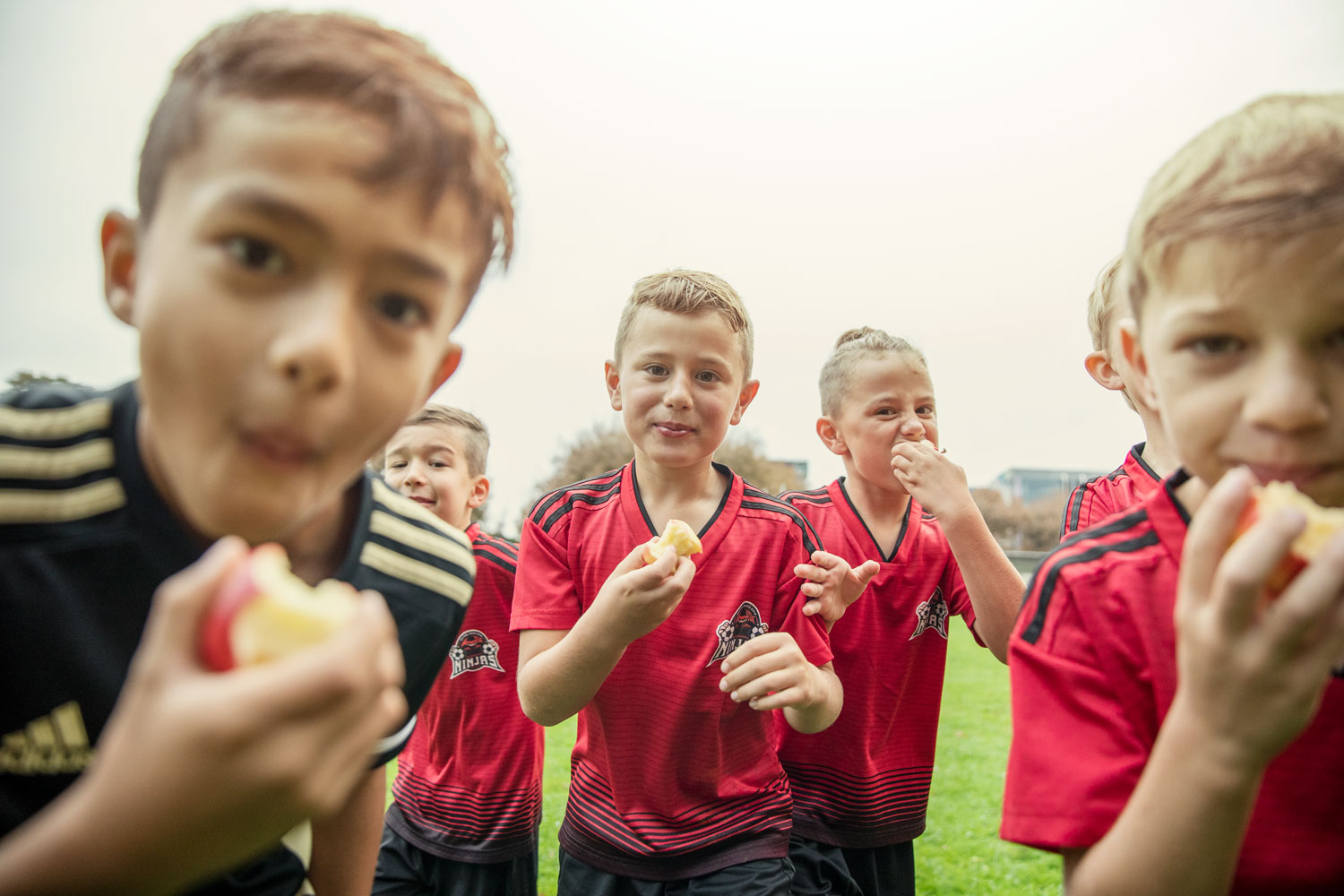Five boys enjoying a Rockit apple after football game