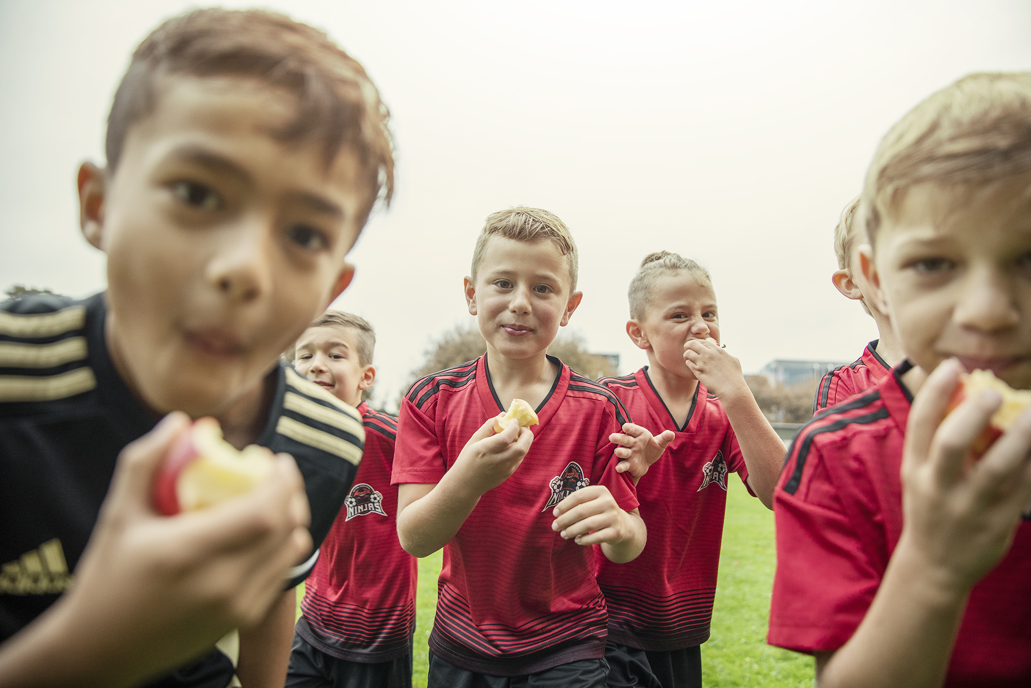 Six young boys eating Rockit apples after football game