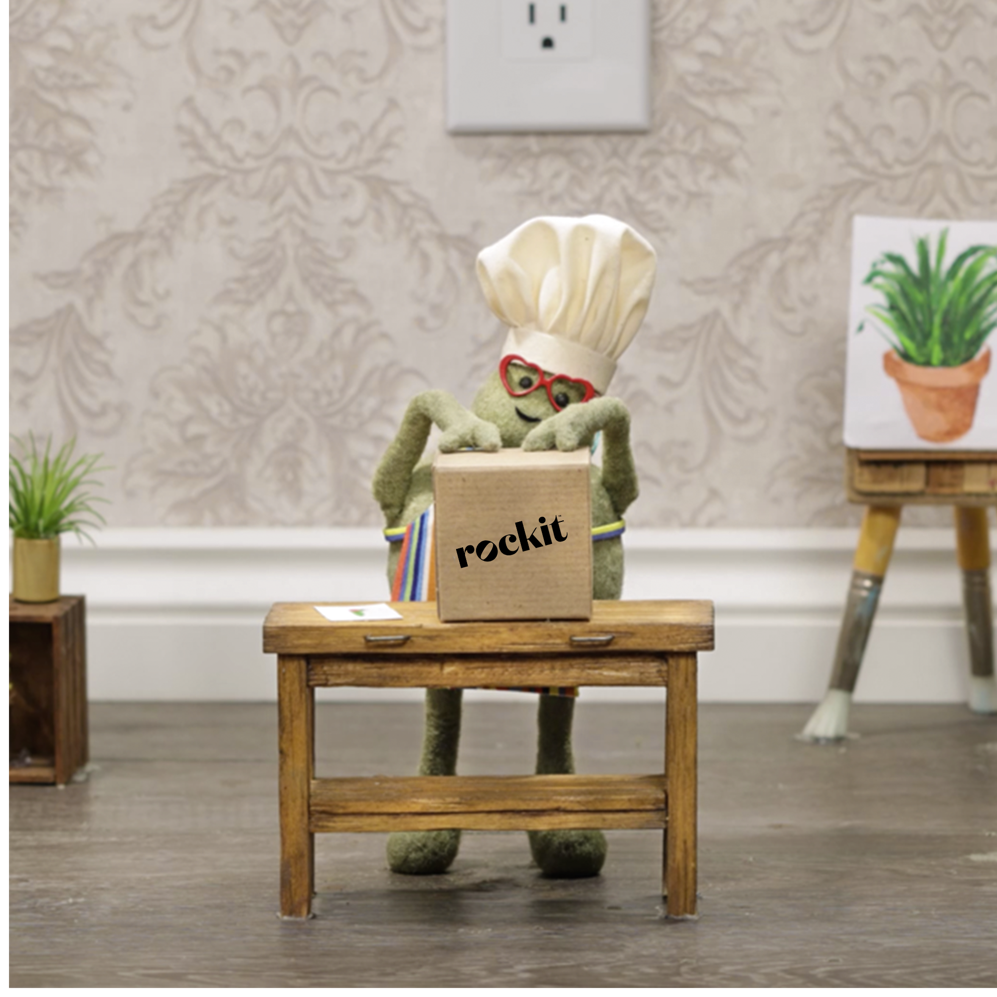 The Tiny Chef opening a brown box that has 'Rockit' written on the front.